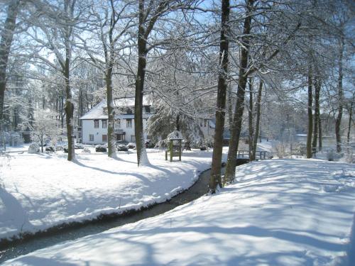 a snow covered driveway with a house in the background at Hotel Wintersmühle in Bielefeld