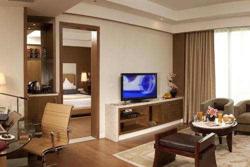 a living room with a television and a room with a bed at Crowne Plaza New Delhi Okhla by IHG in New Delhi
