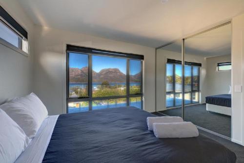 a bedroom with a large bed with a large window at Deja Blu 2 in Coles Bay