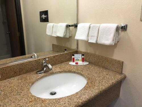 a bathroom with a sink and a mirror and towels at Days Inn by Wyndham Rio Rancho in Rio Rancho
