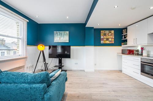 a living room with blue walls and a blue couch at Cozy and Charming Flat: Minutes from Everything! in London