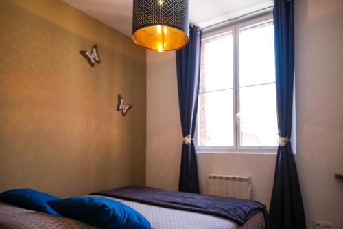ein Schlafzimmer mit einem Fenster und einem Bett mit blauen Kissen in der Unterkunft Le Business House in Saint-Omer