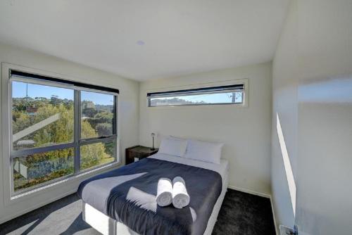 a bedroom with a bed with two white shoes on it at Deja Blu 1 in Coles Bay