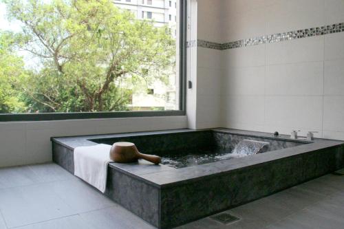 a bath tub in a room with a window at Gamalan Spring Hotel in Jiaoxi