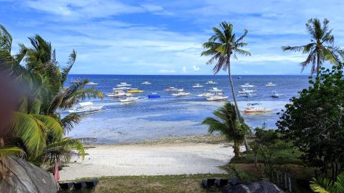 a beach with boats in the water and palm trees at Bohol South Beach Hotel in Panglao