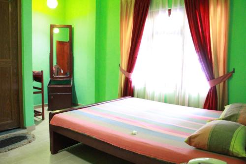 a bedroom with a bed with green walls and a window at Wijaya Tourist INN in Warakapola