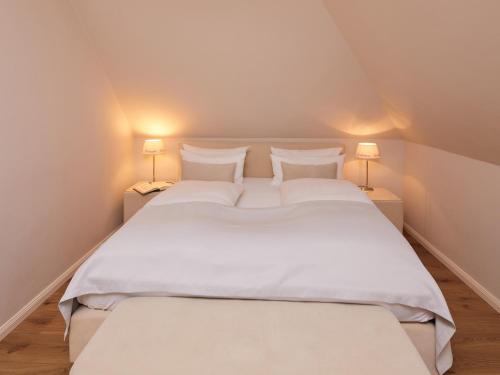 a large white bed in a room with two lamps at Techts Landhus Birkenallee in Timmendorfer Strand