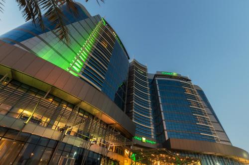 a tall building with a palm tree in front of it at Holiday Inn Abu Dhabi, an IHG Hotel in Abu Dhabi