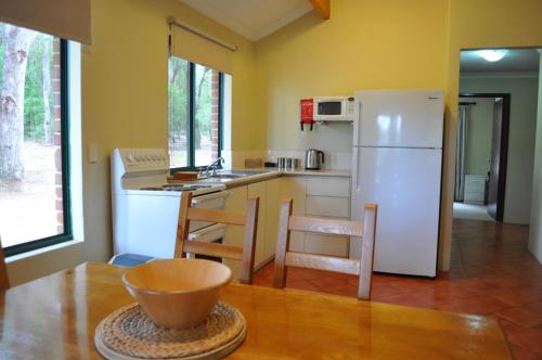 a kitchen with a white refrigerator and a table at Karri Valley Chalets in Pemberton