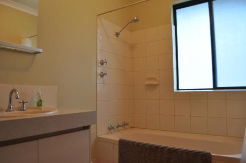 a bathroom with a tub and a sink and a shower at Karri Valley Chalets in Pemberton