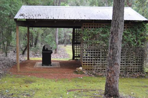 a wooden structure with a roof and a tree at Karri Valley Chalets in Pemberton