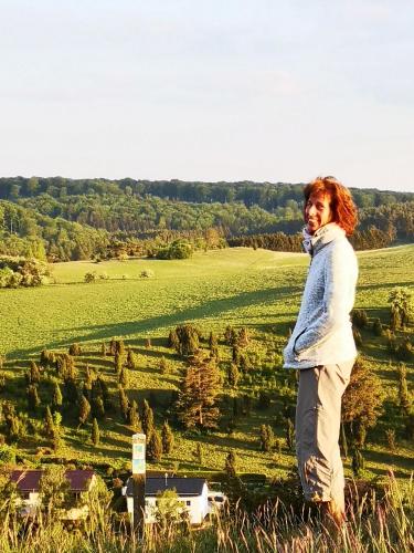 a woman standing on a hill talking on a cell phone at Ferienwohnung Schmahl in Schleiden