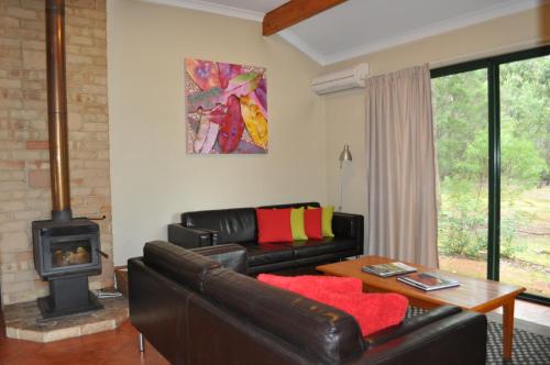 a living room with a leather couch and a wood stove at Karri Valley Chalets in Pemberton