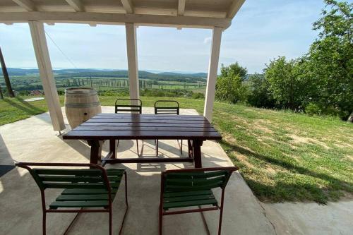 una mesa de picnic y sillas en un porche con vistas en Présház a hegytetőn, en Pécsely