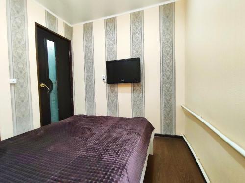 a bedroom with a bed and a tv on the wall at Апартаменты на Сайдашева 3 in Bugul'ma