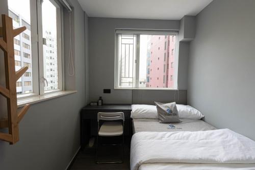 um quarto com duas camas e uma secretária e duas janelas em Studio Stay em Hong Kong