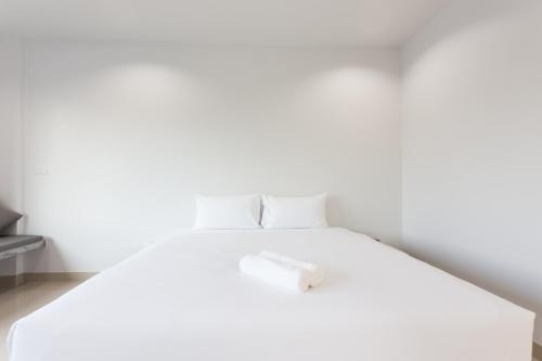 a white bed in a room with a white wall at The Gene in Krabi town