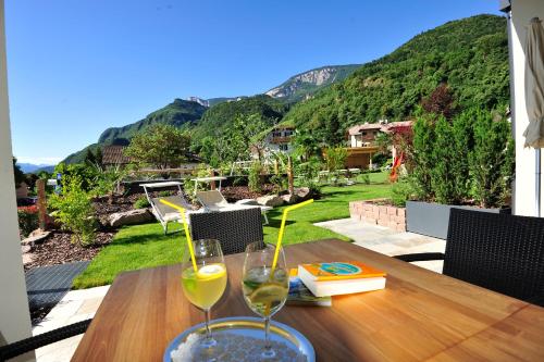 two glasses of wine sitting on a wooden table at Apparthotel Gartenresidence Nalserhof in Nalles