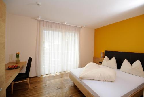a bedroom with a white bed with a yellow wall at Apparthotel Gartenresidence Nalserhof in Nalles