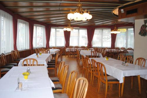 a restaurant with white tables and chairs and windows at Gasthof Knappenwirt in Tamsweg