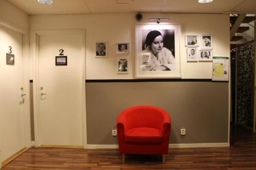 a red chair in a room with a picture on the wall at Klara Hostel Stockholm in Stockholm