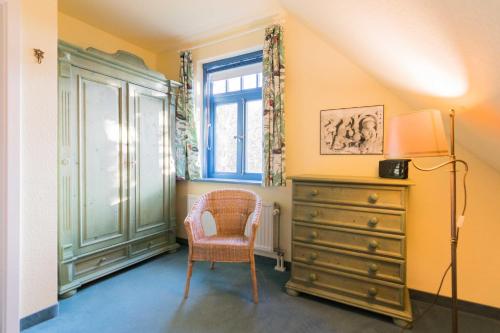 a room with a dresser and a chair and a window at Ferienhaussiedlung Strandperlen Küstenhof 3d (Typ IV) in Wustrow
