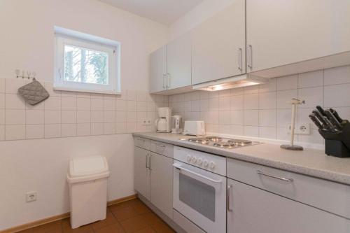 a white kitchen with a sink and a stove top oven at Landhaus DADDELDU Whg. V-D2 (hinten) in Ahrenshoop