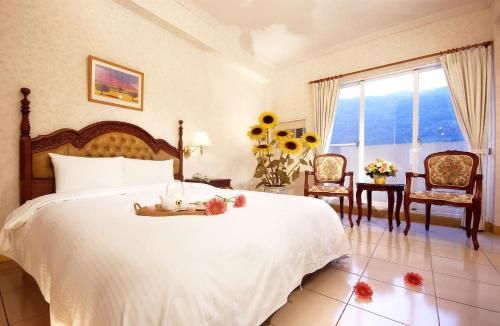 Un dormitorio con una gran cama blanca con flores. en Huang Tai Hotel en Jiaoxi