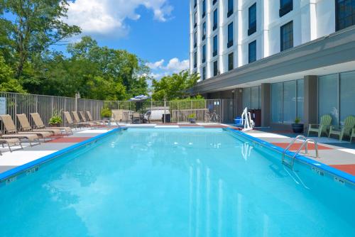 a swimming pool with chairs and a building at Holiday Inn Express Towson- Baltimore North, an IHG Hotel in Towson