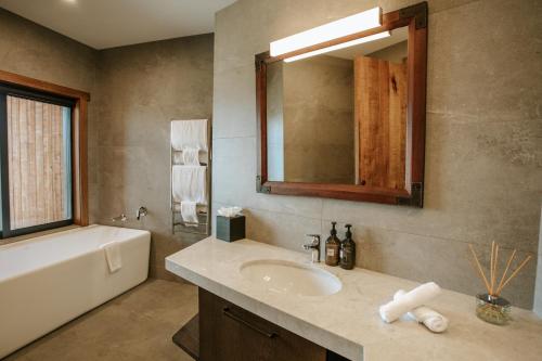 a bathroom with a sink and a tub and a mirror at Stoneridge Estate in Queenstown