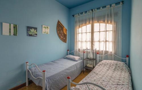 2 camas en una habitación con paredes azules y ventana en Villa Suria en Lloret de Mar