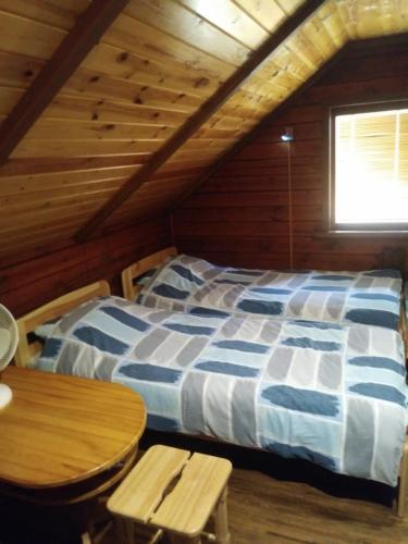 a bedroom with a bed and a table in a cabin at Viesu namiņš Dālderi in Varakļāni