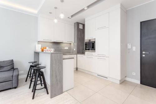 a kitchen with white cabinets and a counter with stools at Chill Apartments Mokotów Residence in Warsaw
