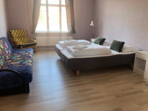 a bedroom with a bed and a chair and a couch at Løgstør Badehotel - Hotel du Nord in Løgstør