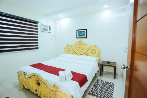 a bedroom with a gold and white bed with shoes on it at OYO 645 Ljenj Apartelle in Mabalacat