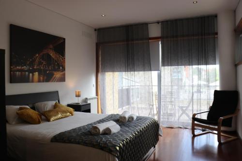 a bedroom with a bed and a chair and a window at Metro Heroismo Residence in Porto