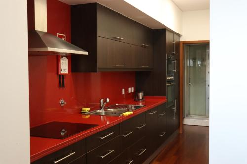 a kitchen with black cabinets and a red counter top at Metro Heroismo Residence in Porto