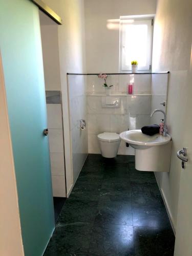 a white bathroom with a toilet and a sink at Dreamapartment La Vigna Living mit eigenem Aussenpool & Sauna - Weil am Rhein in Weil am Rhein