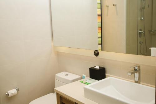 a bathroom with a sink and a toilet and a mirror at Hyatt Place Shenzhen Airport in Bao'an