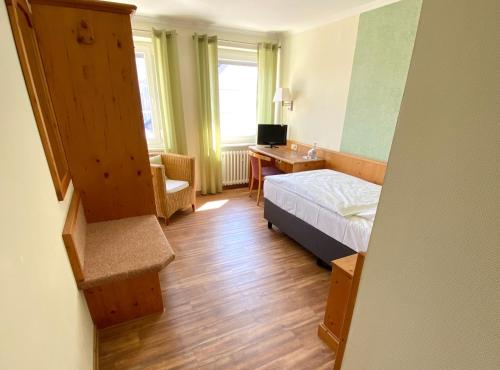 a bedroom with a bed and a desk with a computer at Hotel Deutsches Haus in Kitzingen