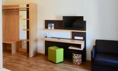 a living room with a desk with a tv and a chair at Hotel Deutsches Haus in Kitzingen