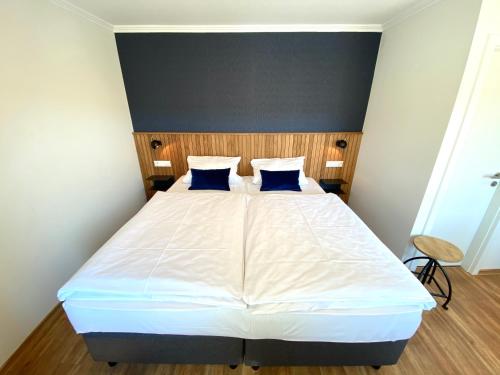 a bedroom with a white bed with blue pillows at Hotel Deutsches Haus in Kitzingen