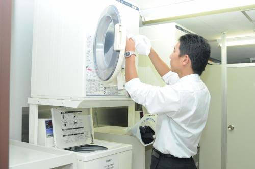 a man is putting a washing machine in a laboratory at Centre One Hotel Handa in Handa