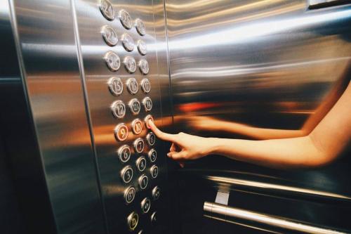 a woman is pointing to an elevator button at BoonRumpa Accommodation in Bangkok
