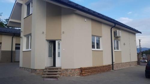 a white house with a door in a parking lot at P&P APARTMÁNY Bojnice in Bojnice