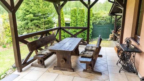 a wooden table and two benches on a patio at Dom Wakacyjny Myśliborka in Nowe Warpno