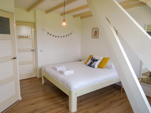 mały pokój z białym łóżkiem i schodami w obiekcie Bed and Breakfast Maas en Waal w mieście Winssen
