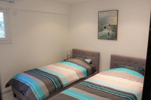 two beds sitting next to each other in a bedroom at Rez de villa avec beau jardin et belle vue in Saint-Laurent-du-Var