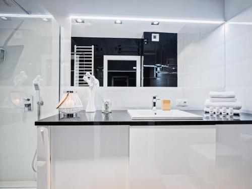 a white bathroom with a sink and a mirror at Apartamenty Homely Place 5 - Parking in Poznań