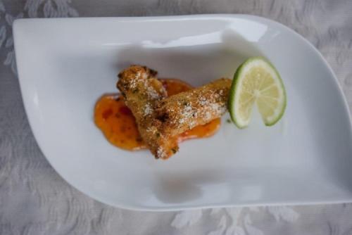 a white plate with a piece of chicken and a lime at Elegant Lodge & Conference Center in Pongola